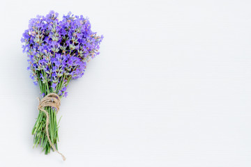 Fresh bouquet of lavender tied up with brown hemp on white wooden background.