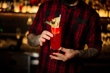 Bartender serving a glass of a Hurricane Punch cocktail on the bar counter