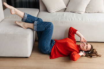 Cheerful young casually dressed woman laying on a floor