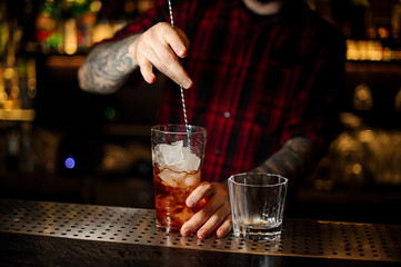 Bartender stirring a Foreign Legion cocktail in the measuring glass with the spoon