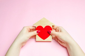 A girl holds a house and heart in her hands. The concept of affordable housing. A dream is to buy a house. Accumulation on the apartment. Property rental. Sale and mortgage real estate. Sweet Home