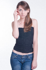 Beautiful young woman in black top and jeans. Fashion studio shoot on bright background. 