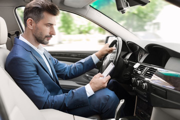 Businessman driving and texting on mobile phone