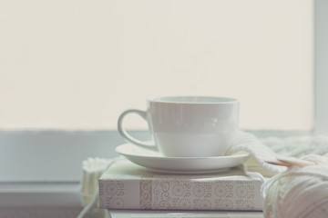 offee Cozy winter home with warm knitted sweaters and ball of yarn  near windowsill, cup of hot coffee marshmallow, home hobbies.  Lifestyle Concept