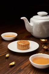traditional mooncake with tea cups, pot and gold ingots isolated on black