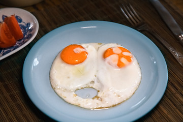 Two fried eggs on plate.Knife and folk, tomatoes.
 Healthy breakfast.
