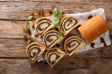 Delicious pastry poppy roll with raisins, nuts decorated with mint close-up on a table. horizontal...