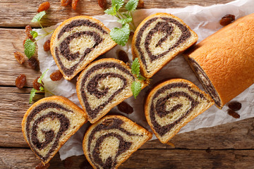 Sweet poppy cake with raisins, decorated with mint close-up on a wooden table. horizontal top view