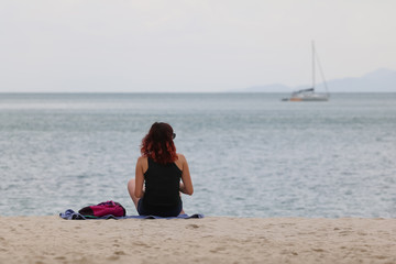 Fototapeta premium Tourist girl reading a book relaxing on a tropical beach in the evening.