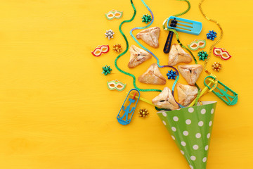 Purim celebration concept (jewish carnival holiday) over wooden yellow background.