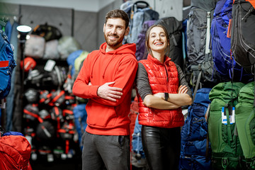 Portrait of a smiling man and woman as a sellers or clients in the shop with sports equipment