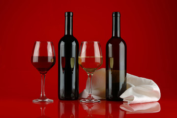 Still life with glasses of wine on a red, glossy background