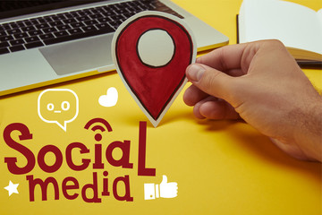 cropped image of man holding paper location sign near laptop with 