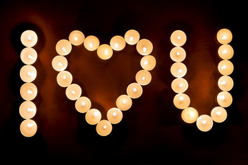 Words I LOVE YOU formed by glowing candles. Greeting to St. Valentine's Day.