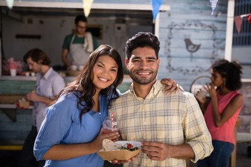 Smiling couple standing with snacks and juice