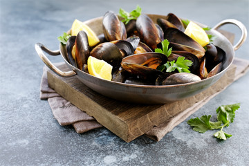 Mussels in cooking dish with parsley and lemon. Close up view