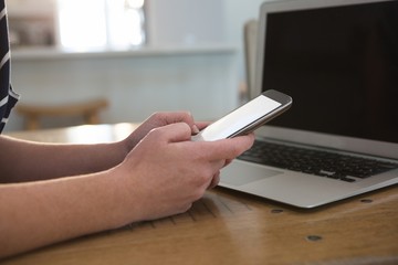 Woman using mobile phone in kitchen at home