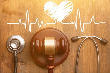 Gavel and stethoscope on wooden background, symbol photo for