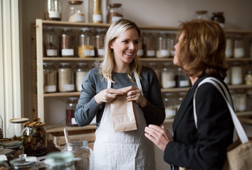 A female shop assistant serving a senior customer in a zero-waste shop.