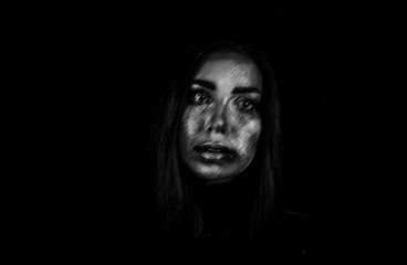 The strange sad woman on a black background, loneliness