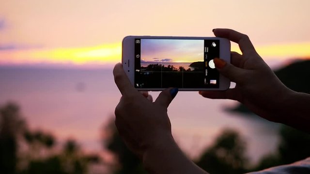 Close up of female hands taking pictures of scenic sea sunset with phone. slow motion. 1920x1080