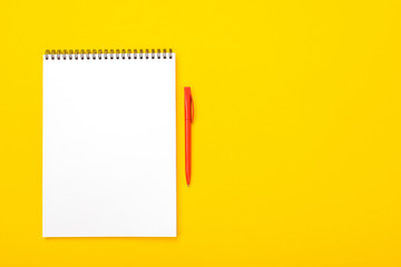Working space table with notebook and pen with copyspace isolated on yellow background
