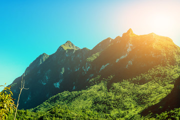 The large green mountains covered with trees and abundant nature consist of blue skies with sunlight shining through. © ronnakon