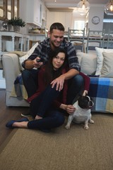 Couple watching television with their pet dog in living room