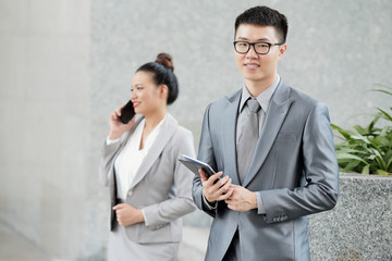 Portrait of handsome young Vietnamese businessman with tablet computer looking at camera