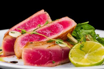 tuna with lime and salad on a black background