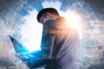 The double exposure image of the business man using a laptop computer during sunrise overlay with cityscape image. The concept of modern life, business, city life and internet of things.