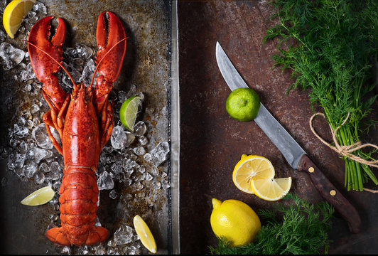 Lobster in a dark grey rusty tray served on ice with lemon and live, top view, vintage style