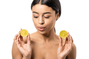 beautiful naked african american girl holding halves of lime and looking down isolated on white