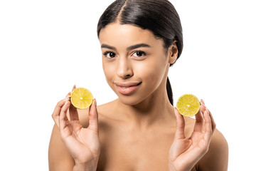 Obraz na płótnie Canvas attractive naked african american girl holding halves of lime and smiling at camera isolated on white