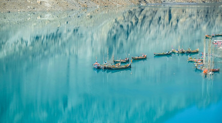 Docked boats in the turquoise Attabad lake with reflection of mountain. Gojal Hunza valley. Gilgit...