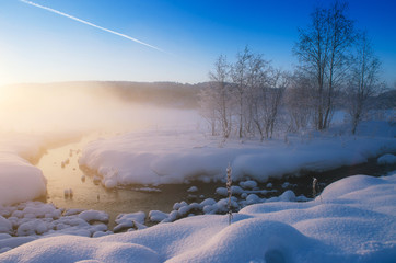 Frozen lake and stream in clear weather at sunset.