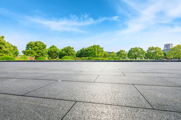 Empty square floor and green trees under blue sky