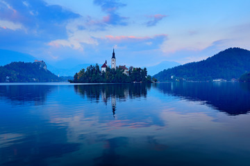 Bled, Slovenia.  lake island, St Martin Catholic church and Castle Landscape in Slovenia, nature in Europe.  Foggy Triglav Alps with forest, travel in Slovenia. Beautiful sunrise with blue sky.