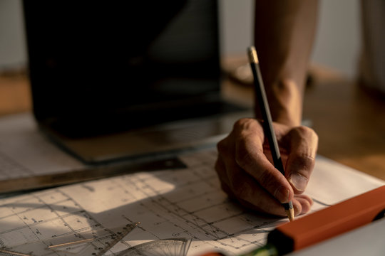 architect or civil engineer during drawing home or building in office on working table with office stationary , laptop ,color pallette sampling.