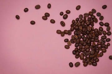 Brown coffee beans on pink background. Copy spase