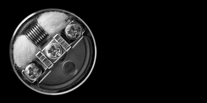 black and white, monochrome shot, top view of single micro coil with japanese organic cotton wick and single coil reducer in high end rebuildable dripping atomizer isolated on black background