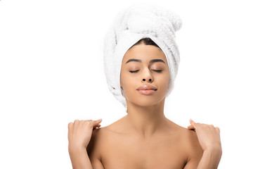 relaxed naked african american woman with closed eyes and towel on head touching shoulders isolated on white