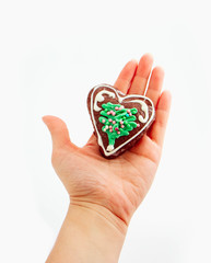 Female hand holding Christmas gingerbread cookie, heart shape, isolated on white. Holiday decoration, winter time food.