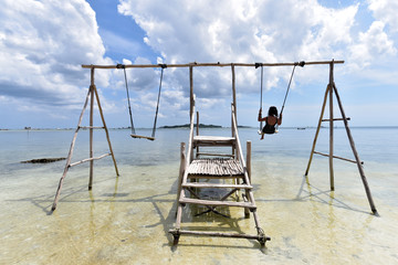 Indonesian girl on a swing at Tanjung Kelayang Beach, Belitung Island, Indonesia