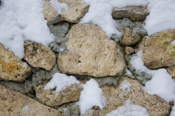 A old stone wall in winter under the snow. Stones under the snow