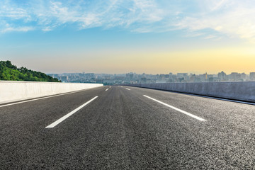 Panoramic city skyline and buildings with empty asphalt road at sunrise