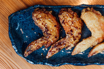Close up Japanese style Salted Chicken Wings and Sticky Sesame Chicken Wings served in blue ceramic plate. 