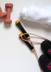 Naklejka premium jump rope, black sneakers, dumbbells, white bath towel, pink close-up on a white background, there is a place for an inscription, vertical frame
