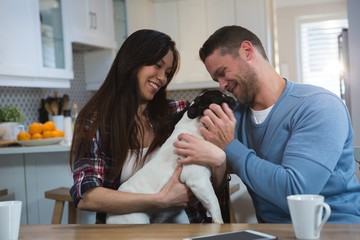 Couple playing with their pet dog in kitchen