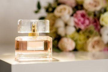 Perfume bottle on table and flowers at background. Aromatic Eau de Toilette